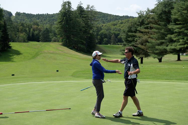 Jim Moretti, of Lebanon, and Paula Dorr, of Grantham, left, reach out for a hug after Moretti sank his team's final putt during the fourth annual Spark golf scramble tournament at Carter Country Club in Lebanon, N.H., Saturday, August 26, 2017. The tournament benefits the Spark Community Center for people of differing abilities. (Valley News - James M. Patterson) Copyright Valley News. May not be reprinted or used online without permission. Send requests to permission@vnews.com.